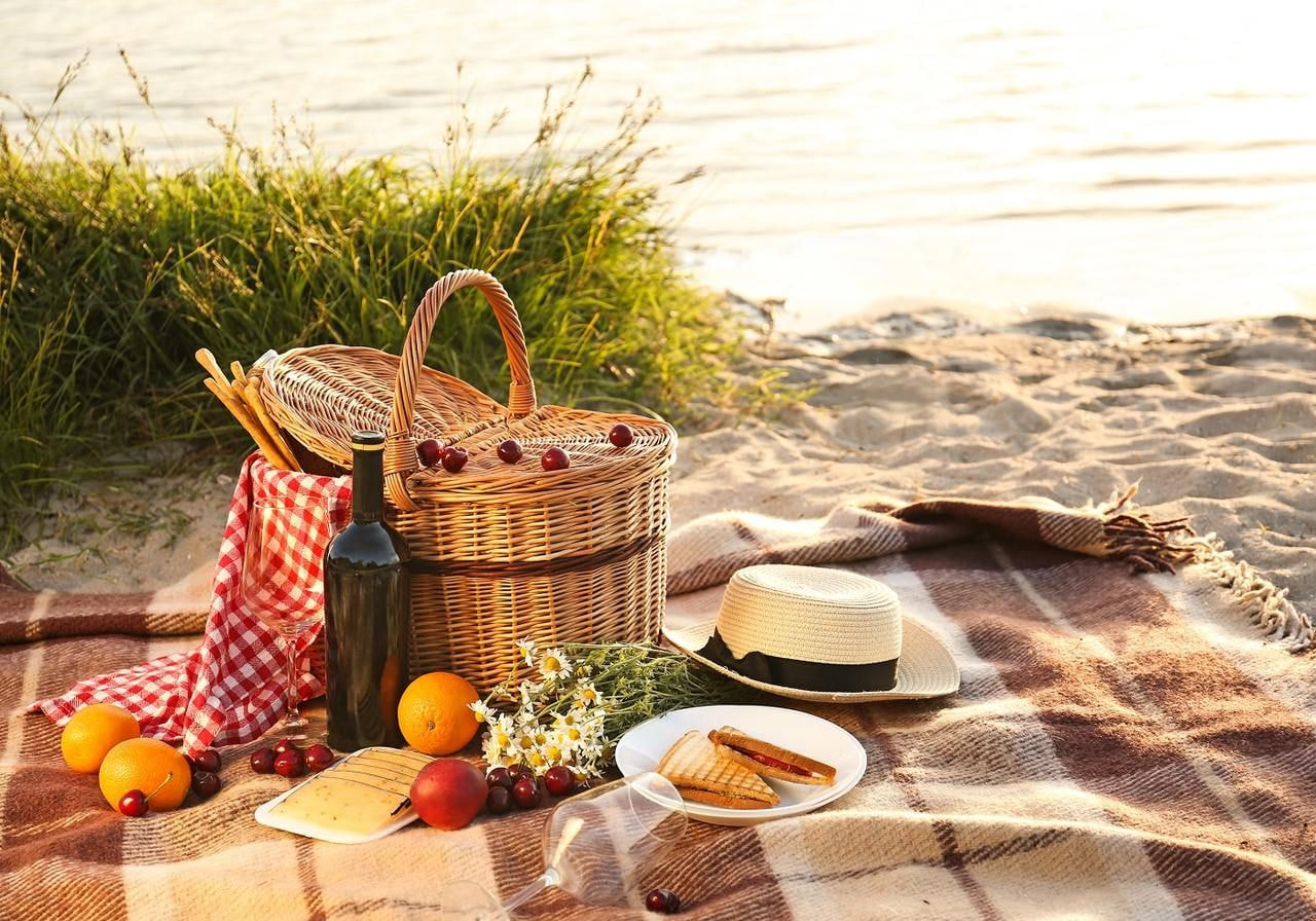 A picnic table set with various foods and drinks, surrounded by a grassy area, ready for a gathering.